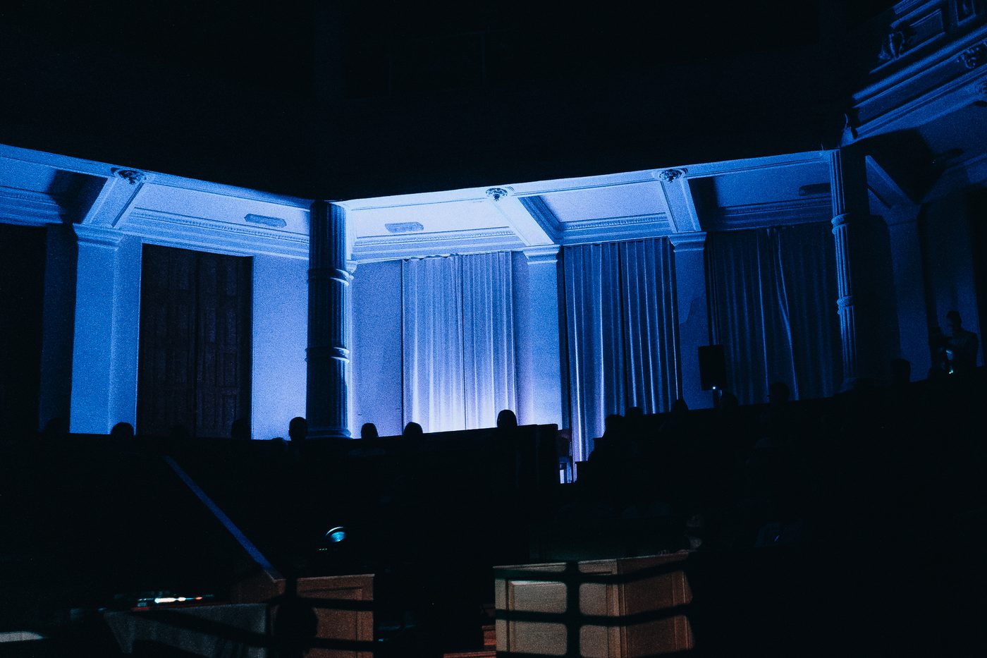 De zaal in blauw licht, publiek als silhouet
